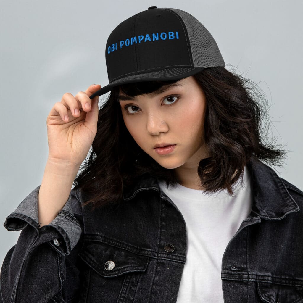 Woman Wearing a Snapback Trucker Hat Obi Pompanobi Font Black Front & Charcoal Grey Back Color